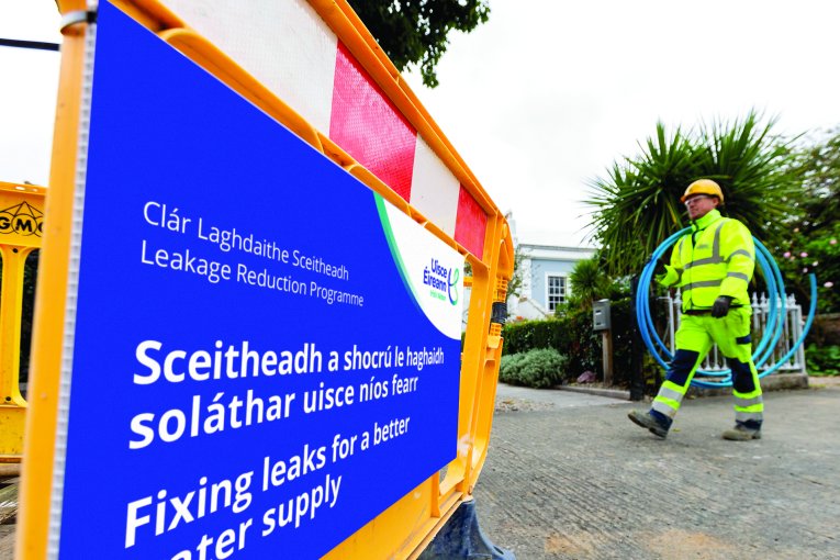 Two Uisce ireann workers putting up a sign for fixing leaks for a better water supply.