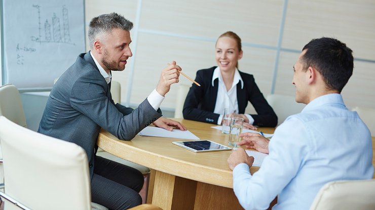 Two men and a woman sitting around a table having a business meeting