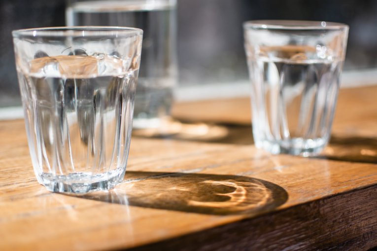 Two glasses of water sitting on a wooden table