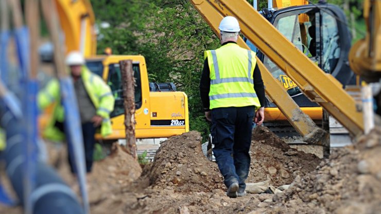 A construction worker walking through a development site surrounded by machinery 