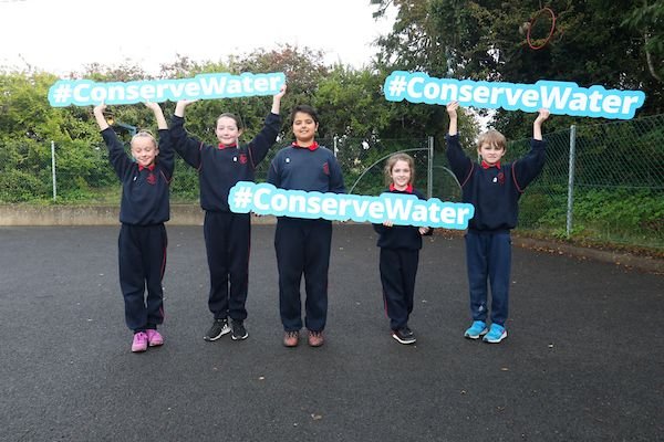 Children at school holding conserve water signs