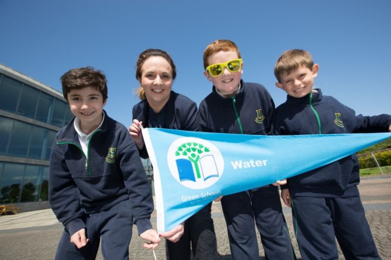 Four children holding a green schools blue water flag