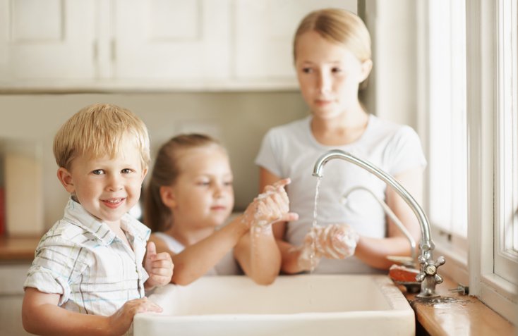 Three children using a sink washing their hands