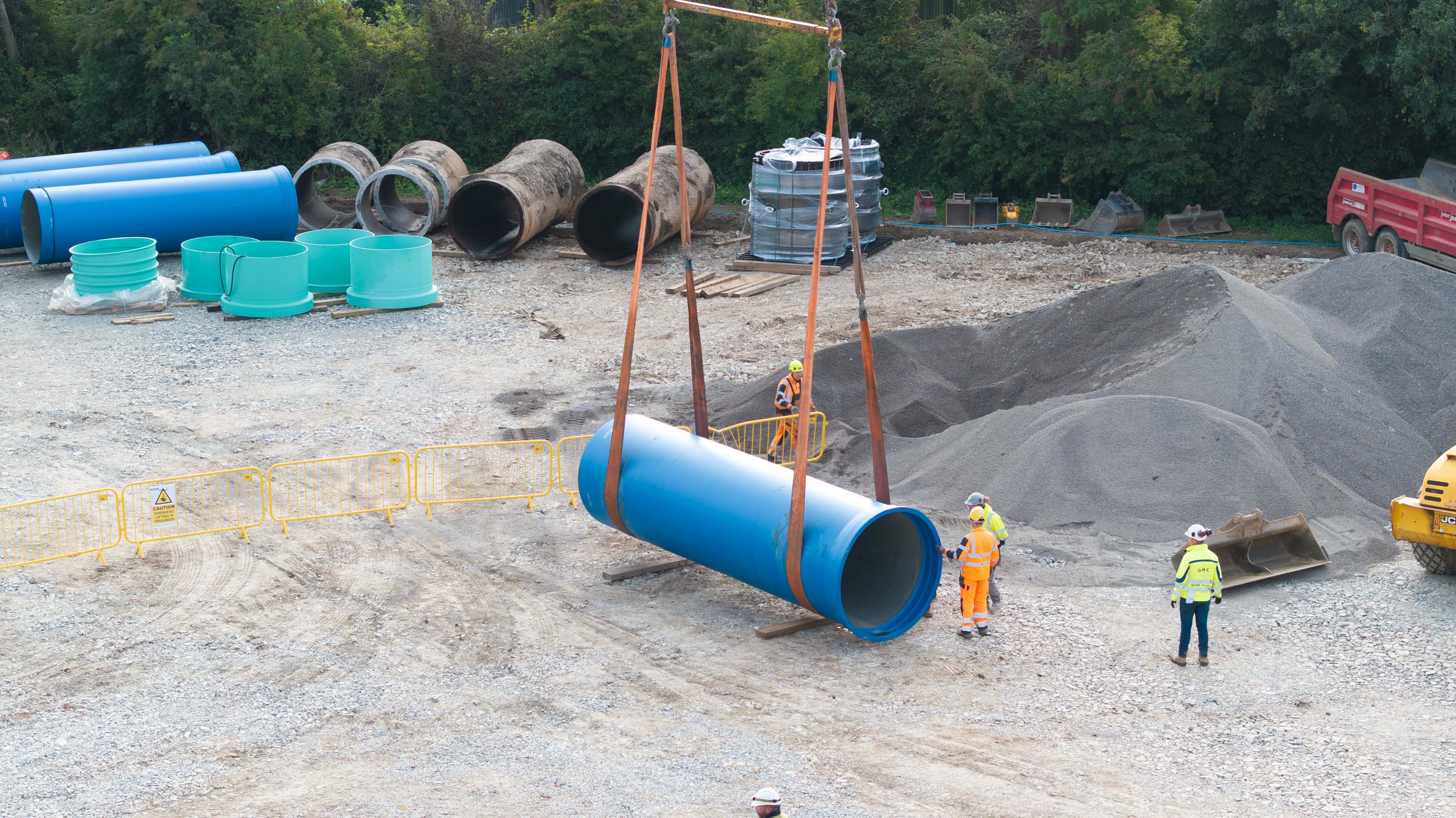 Construction site pipes being lifted by crane