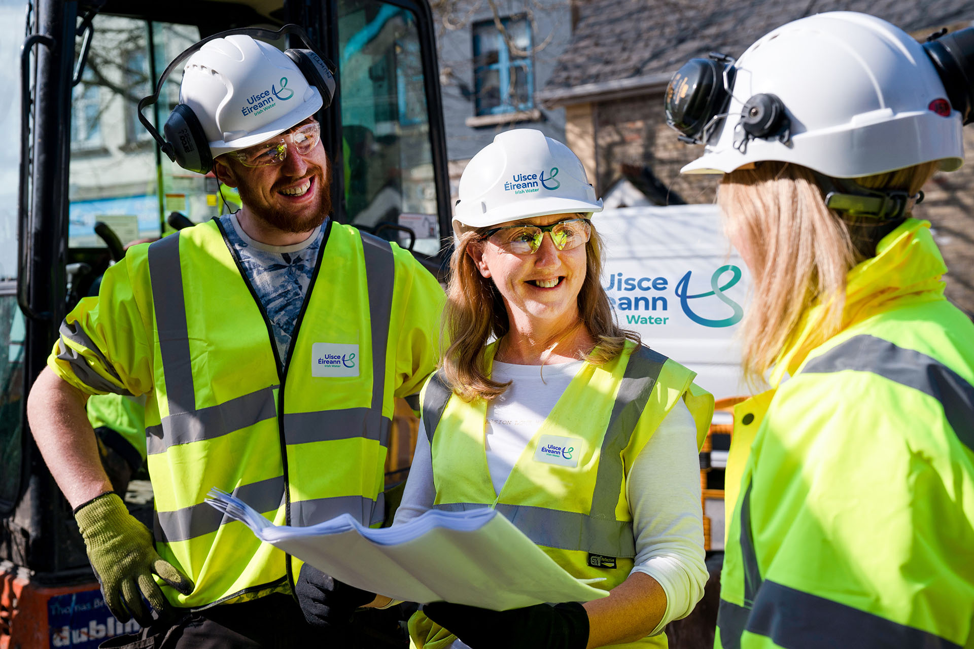 Three Uisce Éireann engineers holding site plans while smiling at eachother