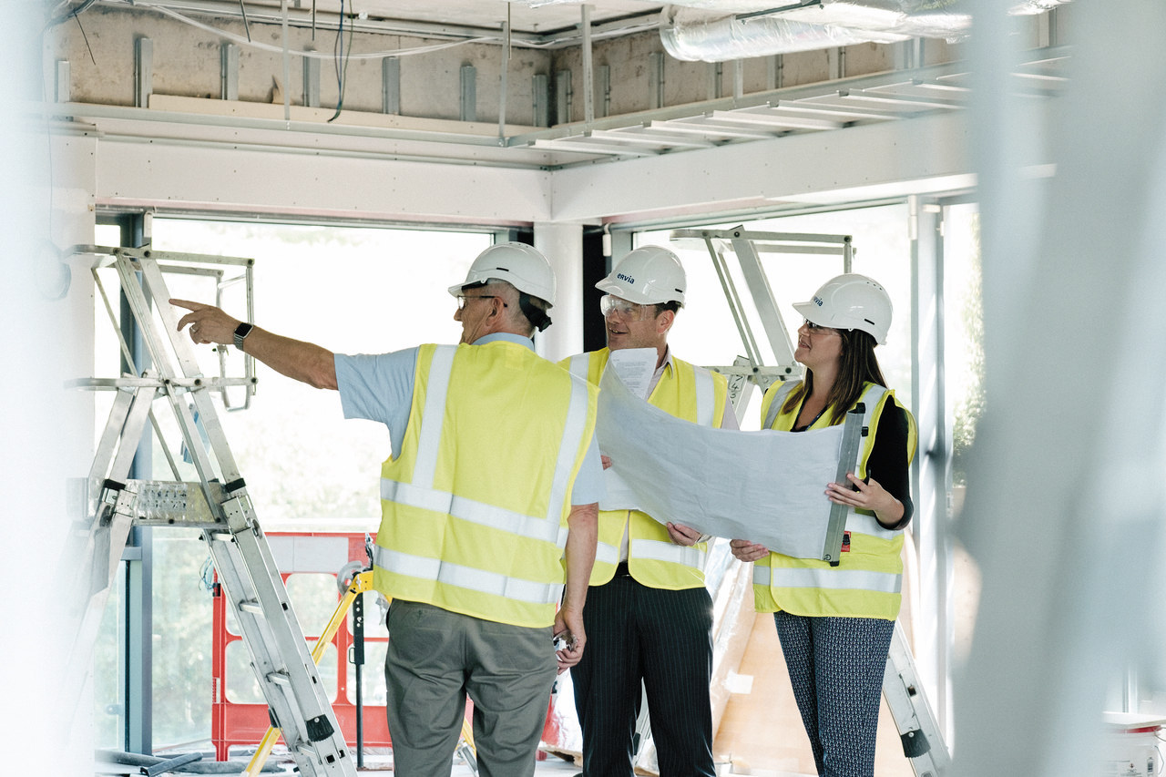 Three Uisce Éireann workers looking at plans while wearing safety gear