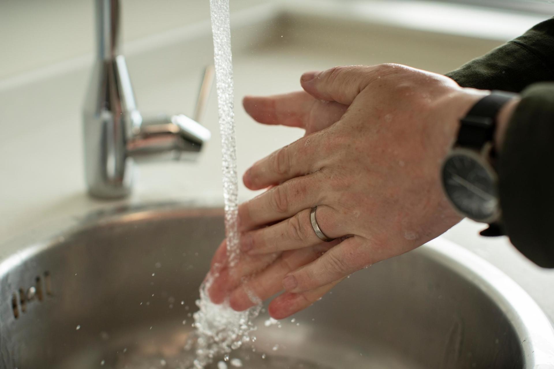 A person washing their hand over a sink