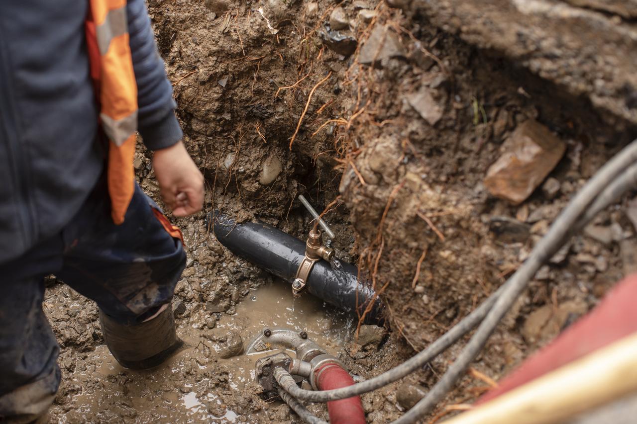 A person standing beside a leak repair underground