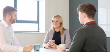 Three UÉ employees sitting around a table with cups of tea
