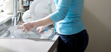 Woman doing dishes by the sink.
