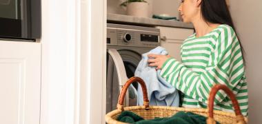 A woman putting clothes in a washing machine