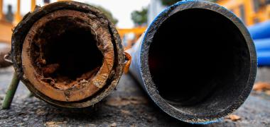 A new clean pipe next to an old damaged and rusty pipe