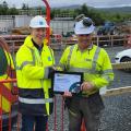 A picture of James O'Gara being handed an award by another person