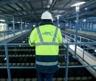 Three men holding a sign that reads "Safeguarding Our Environment" at a water treatment plant