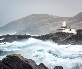 Stormy seas blowing over rocks near a lighthouse