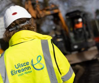 An Uisce Éireann engineer in front of a digger during road works