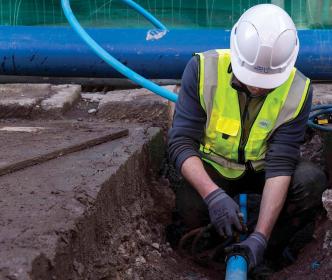Uisce Éireann worker fixing a water pipe on a road