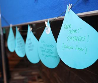 A row of paper cutouts in the shape of drops of water with methods of conserving water written on them