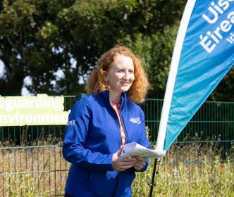 An Uisce Éireann worker by an Uisce Éireann flag and a sign reading "Safeguarding our environment"