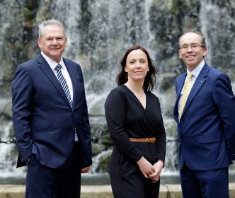 Three people posing for the camera in front of a waterfall