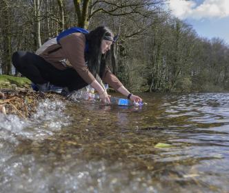 A girl holding a large plastic bottle in a lake