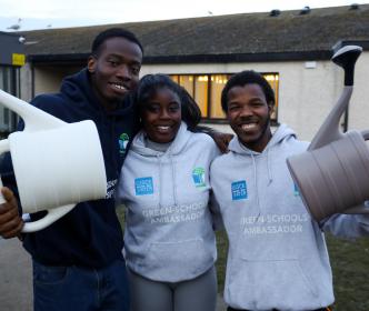 Three students with watering cans and Green-schools Ambassador hoodies