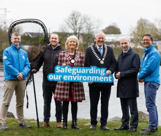 A group of people holding a sign reading 'Safeguarding our environment', with one man holding a large net