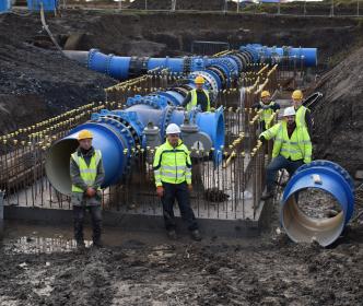 Uisce Éireann workers next to pipes on a site