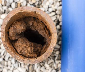 An old  rusty pipe next to a new pipe